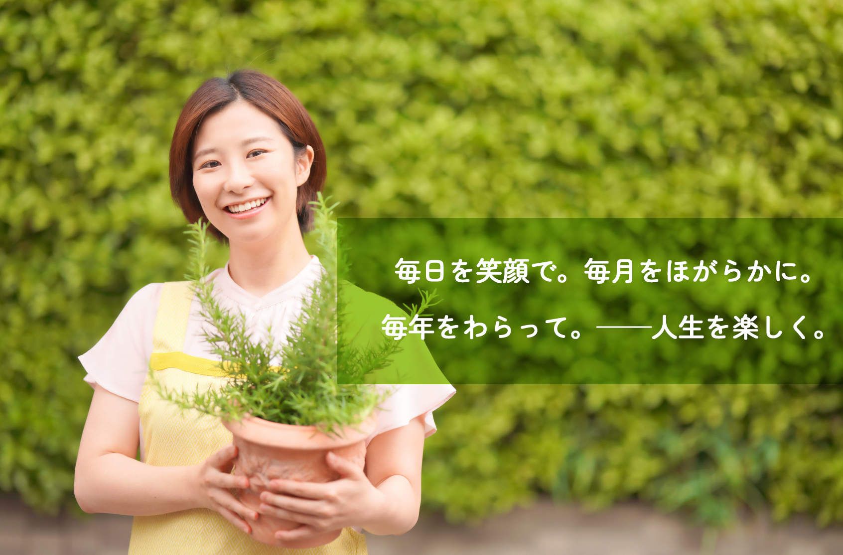 エプロンを付けた笑顔の女性 花笑み3番館のモットーが書いてある